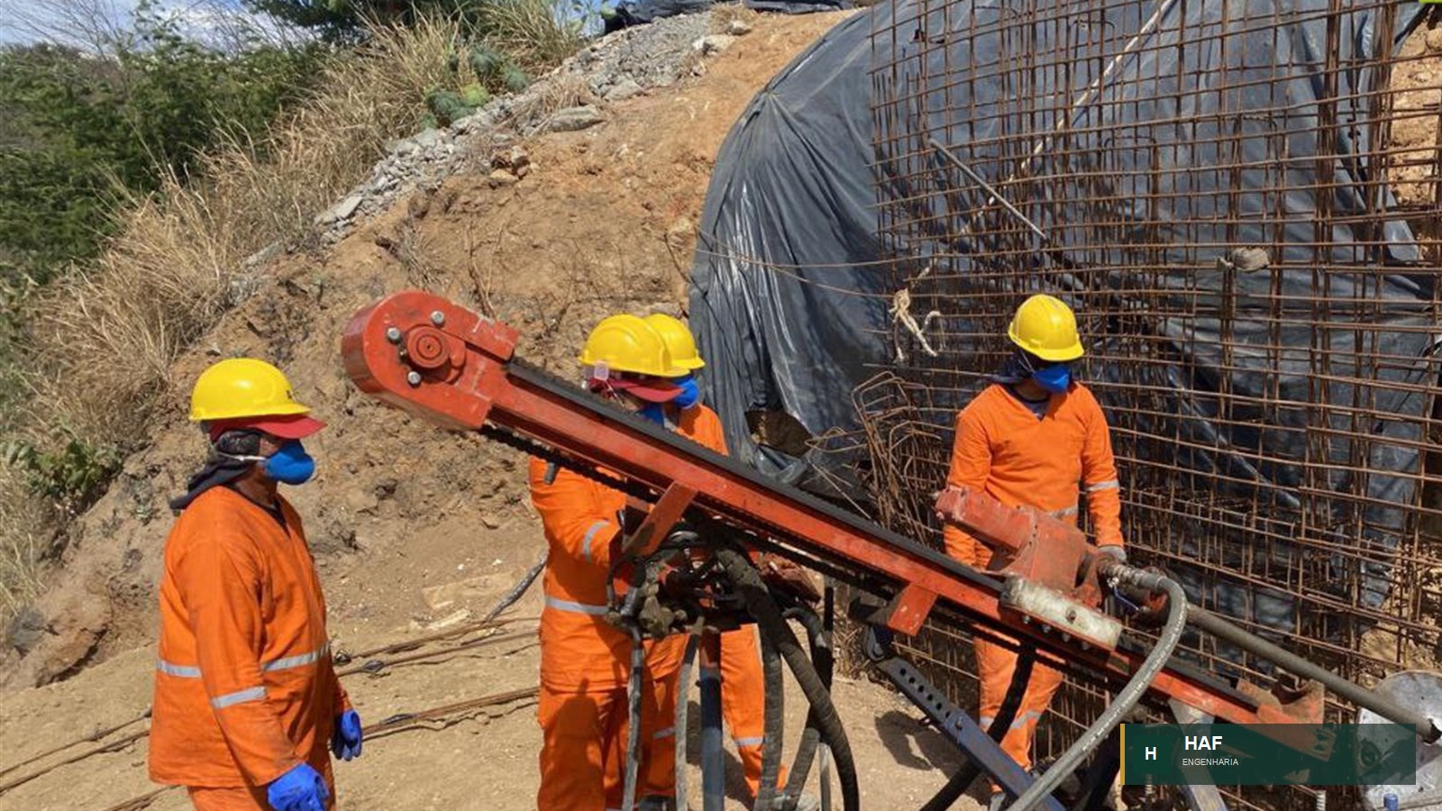 Equipe com equipamento de perfuração junto à armação de cortina atirantada