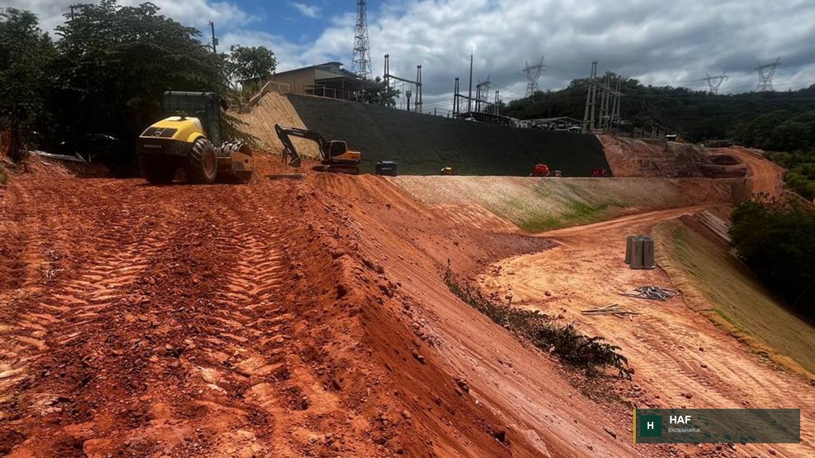 Rolo compactador em plataforma de terraplenagem ao lado de talude de obra